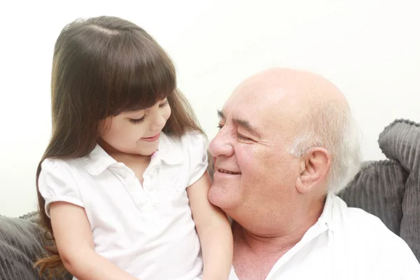 Retrato de avô e neta, sorrindo um para o outro Fotos De Bancos De Imagens