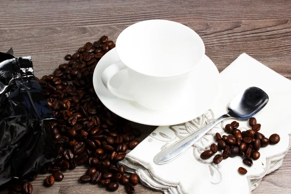 Copa sobre mesa de madera con granos de café —  Fotos de Stock