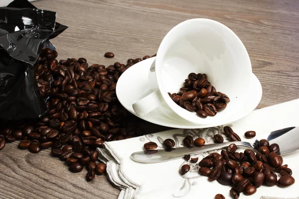 Cup on wooden table with coffeee beans — Stock Photo, Image