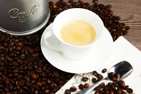 Taza de café sobre mesa de madera con granos de café —  Fotos de Stock