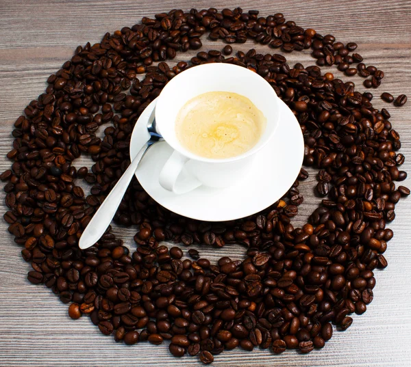 Taza de café sobre mesa de madera con granos de café —  Fotos de Stock