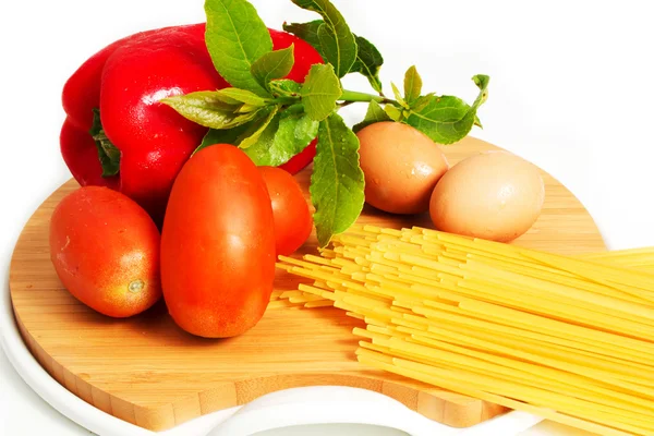 Spaghetti, pasta in tavola con uova, pomodori e peperoni su fondo bianco — Foto Stock