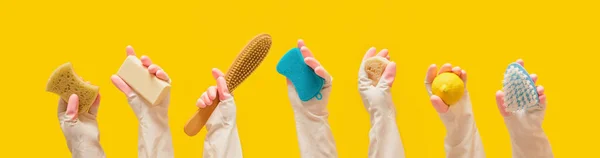eco friendly cleaning tools set on yellow background, general cleaning and cleaning service concept, hands in rubber gloves hold cleaning tools yellow background banner