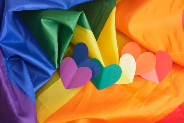 homemade paper hearts in the colors of the lgbt community pride flag on a large fabric flag, love freedom concept