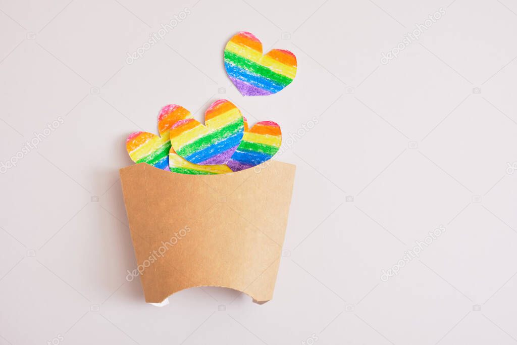 cut out colored paper hearts in packaging for fries on a gray background, lgbt pride concept, fast food cafe for representatives of the lgbt community