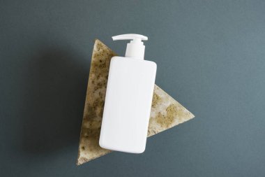 Üçgen taş ve koyu yeşil arka planda beyaz kozmetik şişeler. Etiketsiz birkaç kozmetik paket. üst görünüm kopyalama alanı