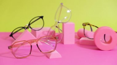 Pembe ang sarı zemin üzerinde çoklu gözlük, geometrik tribünler, yuvarlanan gözlük çerçeveleri geometrik podyumlar