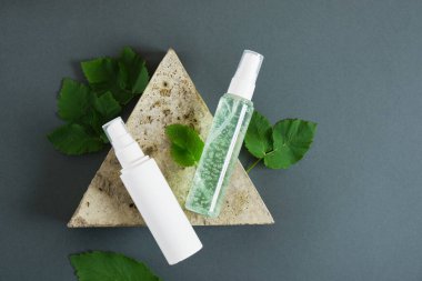 Üçgen taş, kozmetik şişeler ve koyu yeşil arka planda taze nane. Organik kozmetik konsepti. Kozmetik kapları etiketsiz modelleme Doğal cilt ürünü.