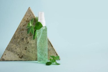 Üçgen taş, yeşil jöleli kozmetik şişe ve açık mavi arkaplanda taze nane şekeri. Eko Doğal Kozmetik Ürün Konsepti. Naneli organik cilt bakımı ürünü
