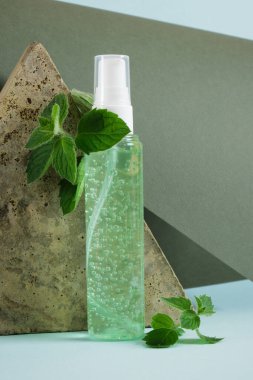 Üçgen taş, yeşil jöleli kozmetik şişe ve açık mavi arkaplanda taze nane şekeri. Eko Doğal Kozmetik Ürün Konsepti. Naneli organik cilt bakımı ürünü