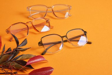 Birkaç farklı moda moda gözlüğü turuncu arka planda kırmızı sonbahar yaprakları fotokopi alanı üst görünümü, sonbahar indirimi, optik mağaza kaktüsleri