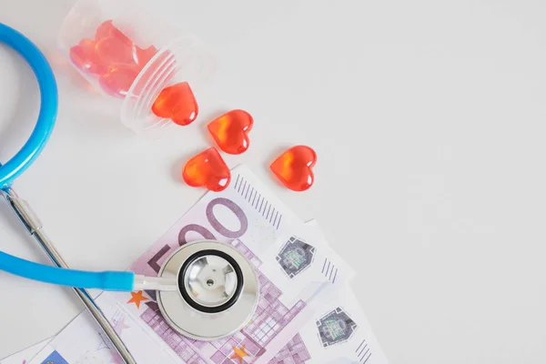 money, hearts in a jar for analyzes and a medical stethoscope on a gray background copy space, sperm and egg donation, artificial insemination and surrogacy concept, euro bills