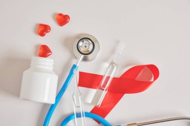 Kırmızı kurdele, hap yerine bir kavanoz kupa ve mavi tıbbi steteskop ve güvenli seks konsepti. Aralık Dünya Yardım Günü ve çoklu miyelom kanseri farkındalığı ayı