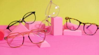 Pembe ang sarı zemin üzerinde çoklu gözlük, geometrik tribünler, yuvarlanan gözlük çerçeveleri geometrik podyumlar