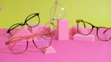 Pembe ang sarı zemin üzerinde çoklu gözlük, geometrik tribünler, yuvarlanan gözlük çerçeveleri geometrik podyumlar