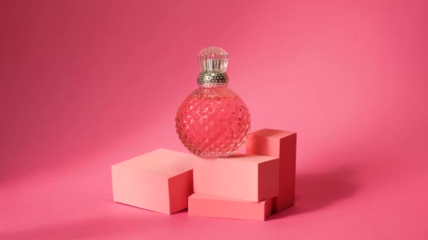 幾何学的な表彰台とピンククリスタル香水スプレーボトルシルバーキャップ ハードシャドウ ピンクの背景に反射やグレア ヤシの葉の影 — ストック動画