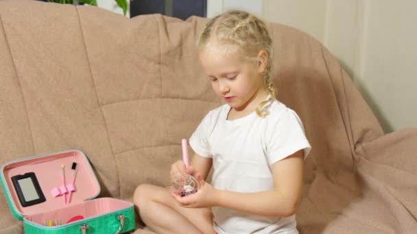 Söt liten flicka med pensel. utgör hennes ansikte på soffan. — Stockvideo
