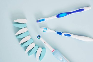 Mavi arka planda elektrikli ve plastik diş fırçaları, diş fırçalarının ağız boşluğunu temizlemede ve çevre dostu çalışmada daha etkilidir.