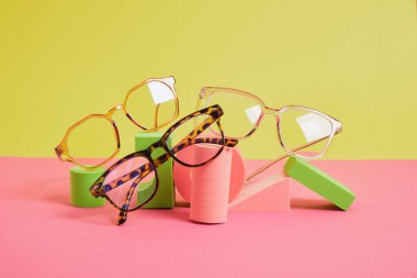 Geometrik pembe podyumlarda birkaç farklı moda göz gözlüğü, renkli arka plan, kopyalama alanı