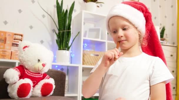 サンタの帽子のかわいい白人の女の子5 6歳はサンタクラス 家庭クリスマスの雰囲気 クリスマスの前夜 休日の準備 クリスマス気分と装飾に手紙を書きます — ストック動画