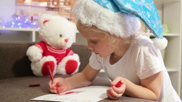 Χαριτωμένο Καυκάσιο Κορίτσι Ετών Ένα Καπέλο Santa Γράφει Ένα Γράμμα — Αρχείο Βίντεο