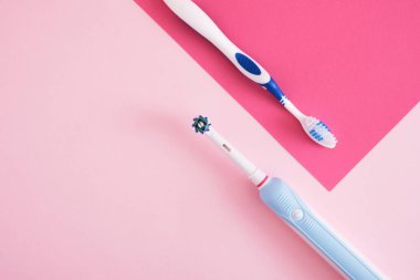 Pembe arka planda farklı diş fırçaları, elektrikli diş fırçası veya plastik diş fırçası, çevre dostu yaşam tarzı konsepti, diş fırçalama etkinliği