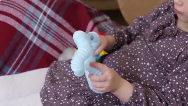 Мила дівчина з кучерявим світлим волоссям грає з поп-іграшкою труби, що сидить на стільці — стокове відео