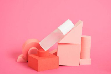 Geometrik stantlar üzerinde cam parfüm şişesi pembe arkaplan fotokopi alanı