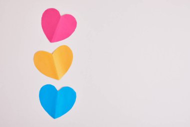 Gri arka planda gökkuşağı renkli kağıt kalpler, lgbt konsepti panseksüelliğin renginde üç kağıt kalp