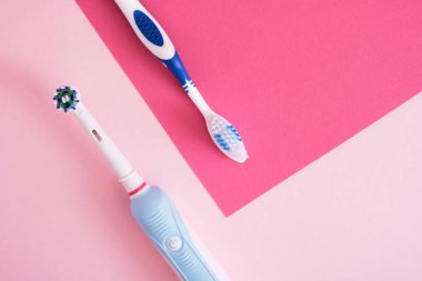 Pembe arka planda farklı diş fırçaları, elektrikli diş fırçası veya plastik diş fırçası, çevre dostu yaşam tarzı konsepti, diş fırçalama etkinliği