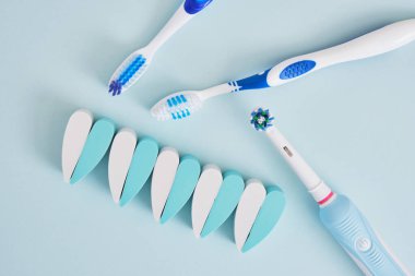 Mavi arka planda elektrikli ve plastik diş fırçaları, diş fırçalarının ağız boşluğunu temizlemede ve çevre dostu çalışmada daha etkilidir.