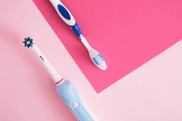 different toothbrushes on pink background, electric toothbrush or plastic toothbrush, environmental friendliness lifestyle concept, efficiency of brushing teeth