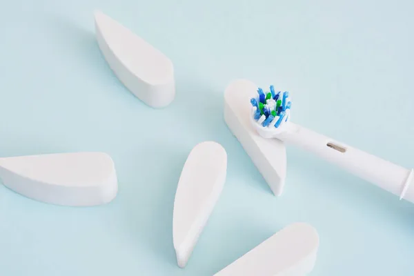 creative composition of electric toothbrush and teeth on a blue background, which brushes are more effective in cleaning the oral cavity and more eco-friendly
