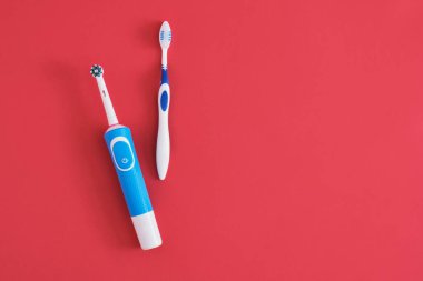 kırmızı arka planda farklı diş fırçaları, elektrikli diş fırçası veya plastik diş fırçası, çevre dostu yaşam tarzı konsepti, diş fırçalama etkinliği