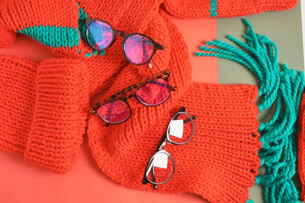 several different stylish eye glasses on a red knitted scarf, christmas sale in optics store, trendy eyeglass frames