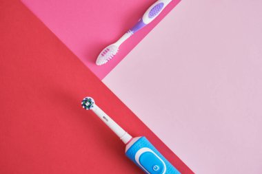 Pembe arka planda farklı diş fırçaları, elektrikli diş fırçası veya plastik diş fırçası, çevre dostu yaşam tarzı konsepti, diş fırçalama etkinliği