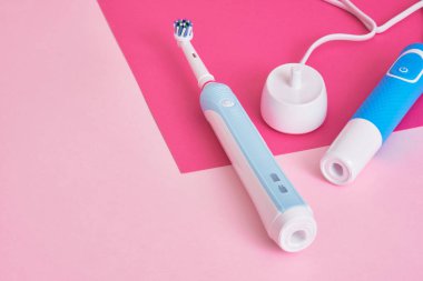 elektrikli mavi diş fırçaları ve onlar için şarj istasyonu pembe arka plan fotokopi alanı, ağız temizliği konsepti