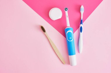 Diş ipi, elektrik, bambu ve pembe arkaplandaki plastik diş fırçaları, diş fırçaları ağız boşluğunu temizlemede daha etkili ve çevre dostu.