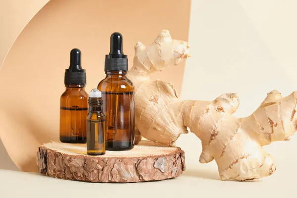 mock up amber glass dropper bottles and ginger root on beige background copy space natural cosmetic concept, bottles with oil or serum on wooden stand, aroma therapy selective focus