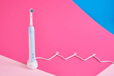 elektrikli mavi diş fırçası ve onlar için şarj istasyonu pembe arka plan fotokopi alanı, ağız hijyeni konsepti