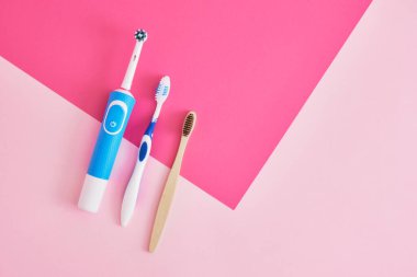 Pembe arka planda çeşitli diş fırçaları, elektrik, bambu ve plastik diş fırçaları, çevre dostu yaşam tarzı konsepti, plastik geri dönüşümü