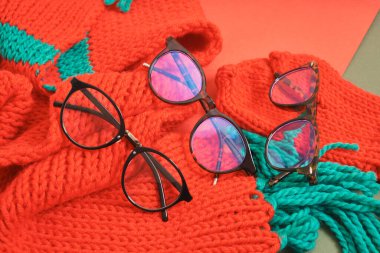 Kırmızı örgü bir eşarpta birkaç farklı gözlük, optik mağazasında noel indirimi, moda gözlük çerçeveleri.