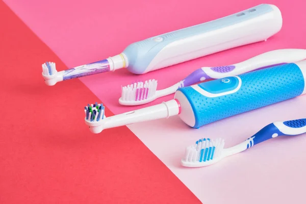 assorted toothbrushes on pink background, electric toothbrushes or plastic toothbrushes, which brushes are more efficient and more environmentally friendly