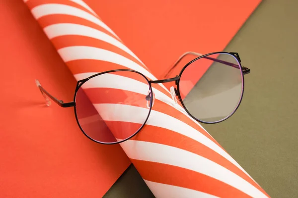 时髦的眼镜和一卷带条纹的包装纸 光学商店里的圣诞特价商品 时髦的眼镜镜框 节日气氛 — 图库照片