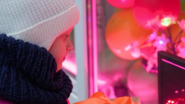 Egy kislány karácsonyi ajándékdobozzal narancssárga szalaggal. karácsonyi ünnepek koncepciója — Stock videók