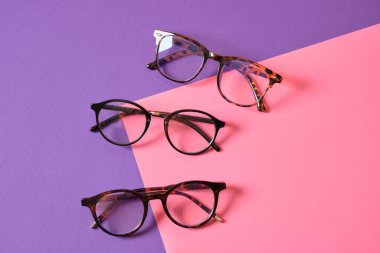 Pembe ve mor geometrik arkaplanda farklı moda gözlükleri, modaya uygun gözlük çerçeveleri boşluğu kopyalıyor