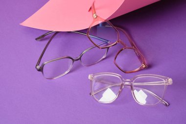 Pembe ve mor geometrik arkaplanda farklı moda gözlükleri, modaya uygun gözlük çerçeveleri boşluğu kopyalıyor