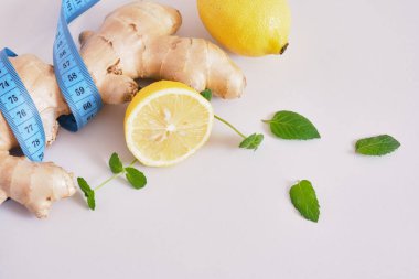 limon, nane yaprağı, zencefil kökü ve mavi ölçü bandı gri arka plan fotokopi alanı, kilo kaybı konsepti, doğal diyet içeceği