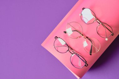 Pembe ve mor geometrik arkaplanda farklı moda gözlük, rulo kağıt ve moda gözlük çerçeveleri boşluk kopyala