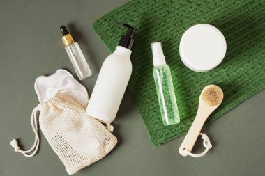 Üzerinde yeşil örgü eşarp ve koyu yeşil arka planda kozmetik ürünleri olan beyaz şişeler ve kavanozlar. Güzellik ürünlerinin Noel indirimi konsepti. Boşluğu kopyala